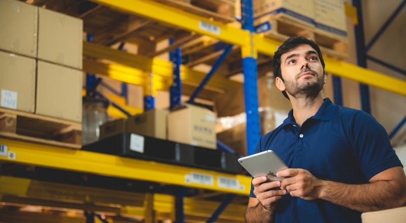 Warehouse worker managing inventory with a tablet.