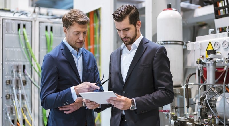 Two executives in the factory reviewing the Master Production Schedule (MPS).